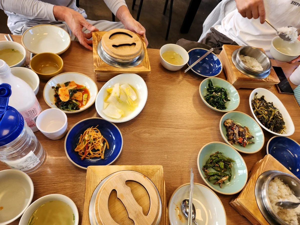 여러 사람이 돌솥밥과 반찬을 함께 즐기는 모습